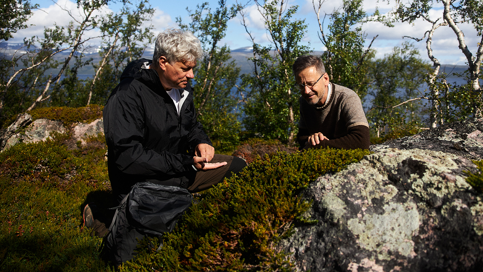 Nature is what we do 7 Two men closely inspecting plants on a cliff.