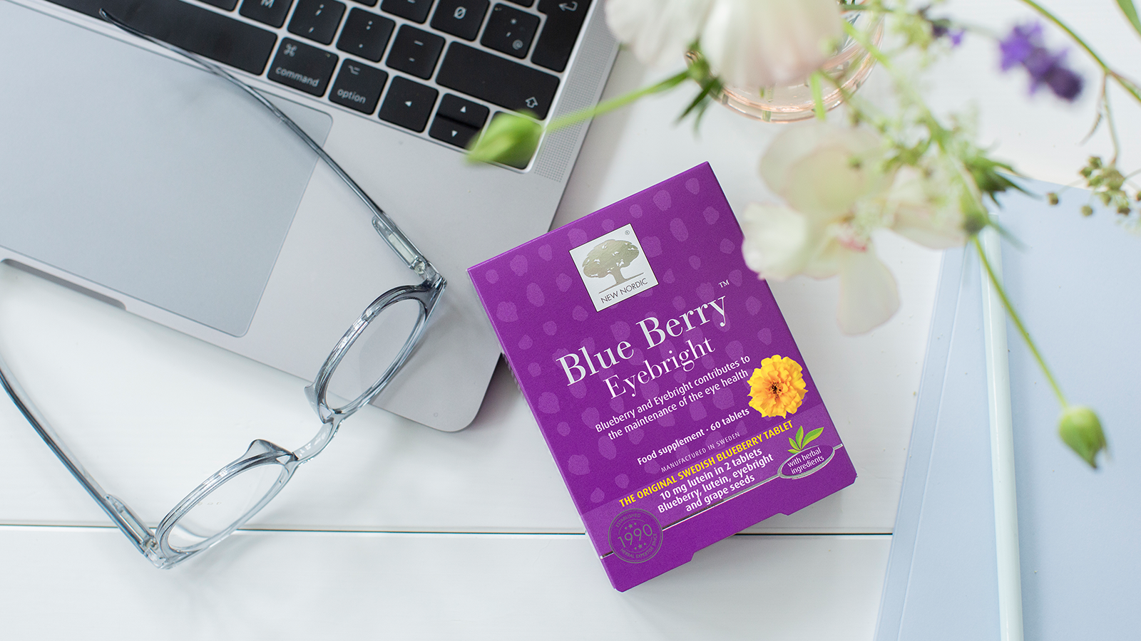 A pack og Blue Berry tablets on a table with a laptop and a pair of classes